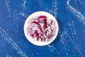 Free photo white plate of sliced purple onions on marble surface