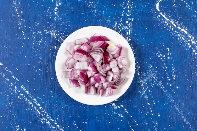 White plate of sliced purple onions on marble surface