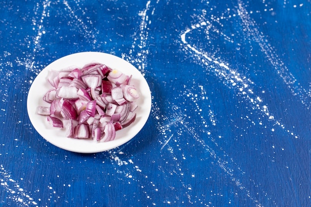 White plate of sliced purple onions on marble surface