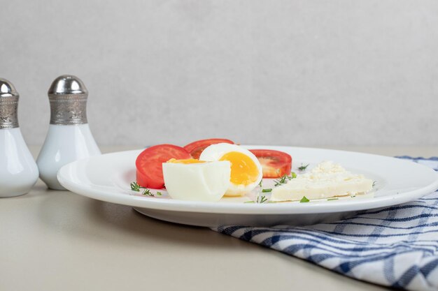 A white plate of sliced tomato and boiled egg .