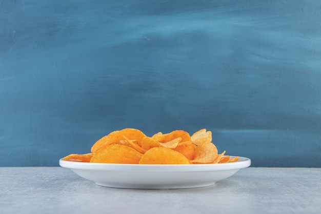 White plate of spicy chips placed on stone.