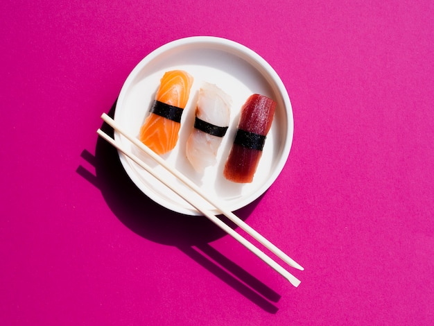 White plate of sushi with chop sticks on a rose background