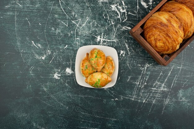 White plate of sweet bakery and wooden basket of gogals .