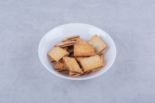 White plate of tasty crunchy crackers on stone table. 