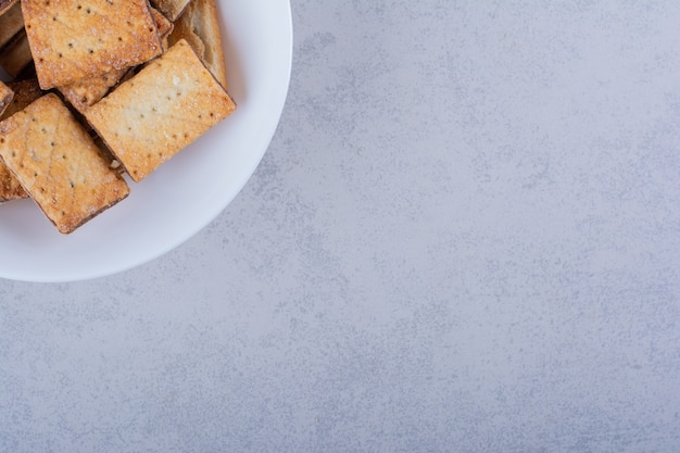 White plate of tasty crunchy crackers on stone.