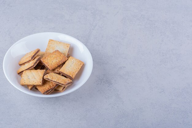 White plate of tasty crunchy crackers on stone.