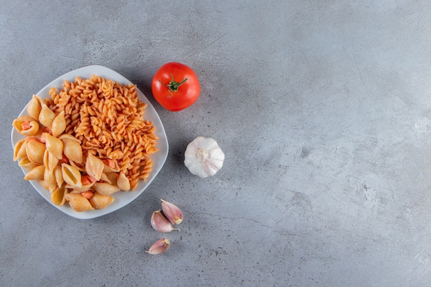 White plate of two various creamy pasta on stone background. 