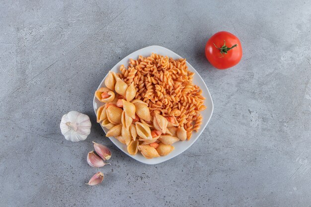 White plate of two various creamy pasta on stone background. 