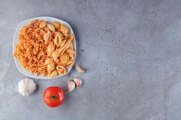 White plate of two various creamy pasta on stone background. 