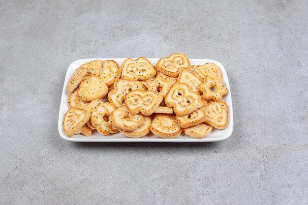 A white plate with biscuits on it on marble background.