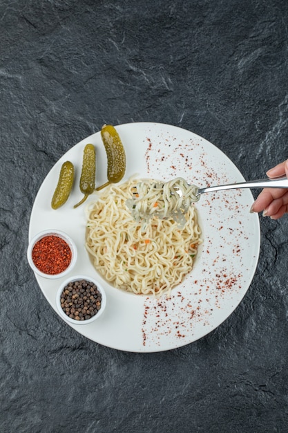 Free photo a white plate with delicious noodles and pickled gherkins.