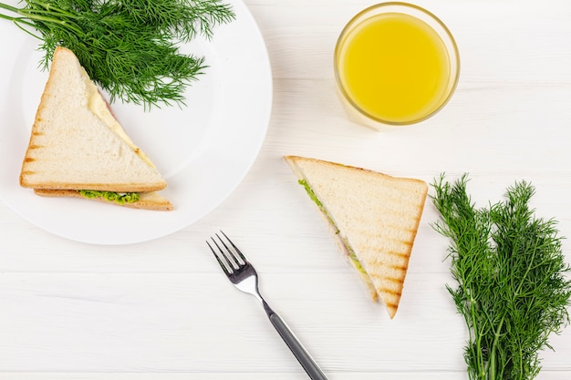 Бесплатное фото Белая тарелка с укропом и бутерброд на белом столе