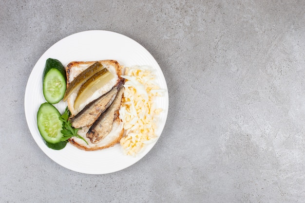 A white plate with fried toast and sprats 