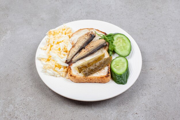 A white plate with fried toast and sprats 