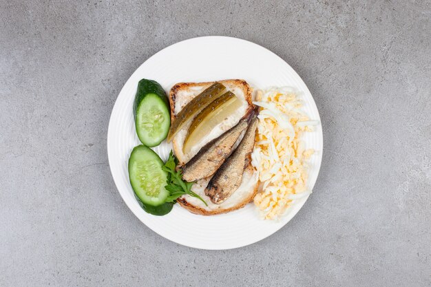 A white plate with fried toast and sprats 