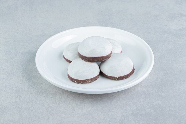 A white plate with gingerbread cookies with icing sugar . 