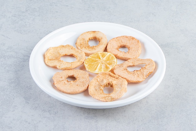 A white plate with healthy dried fruits on marble background.