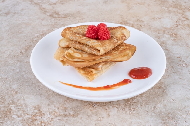 A white plate with pancakes and berries