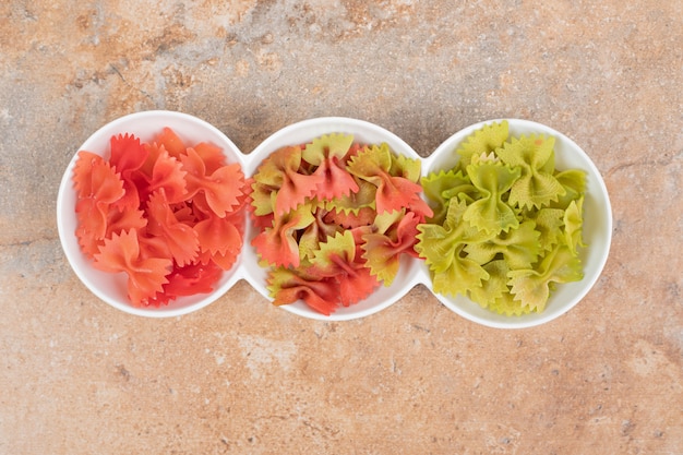 A white plate with red and green uncooked macaroni . High quality photo