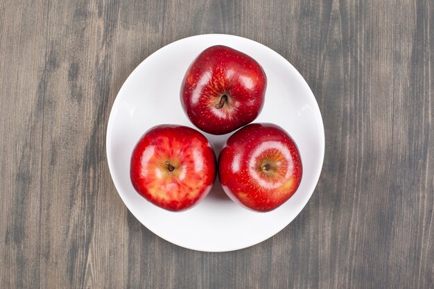 나무 테이블에 붉은 육즙 사과와 흰 접시. 고품질 사진