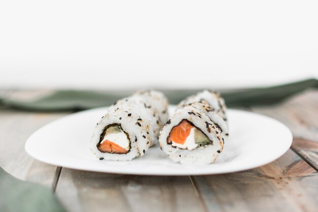 White plate with sushi on wooden table
