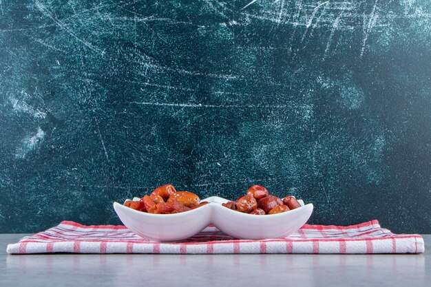 Piatto bianco con vari deliziosi frutti secchi su sfondo di pietra.