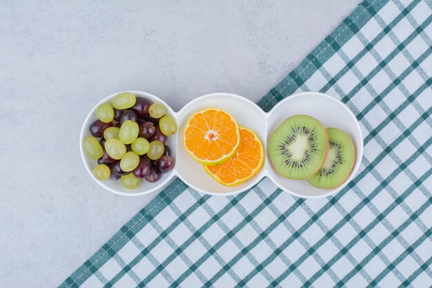 Piatti bianchi di frutta fresca sulla tovaglia. foto di alta qualità