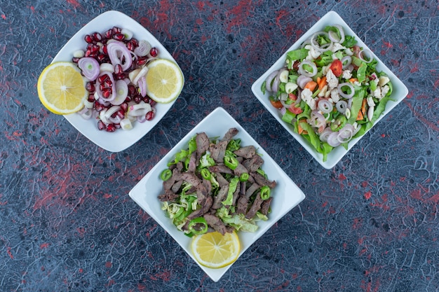 White plates of meat and vegetable salads.