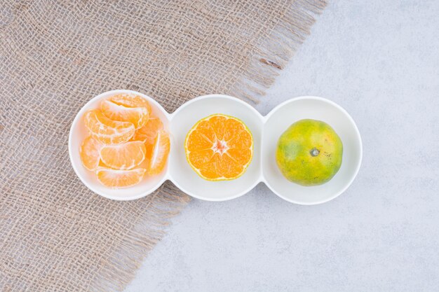 A white plates of peeled tangerines on sackcloth