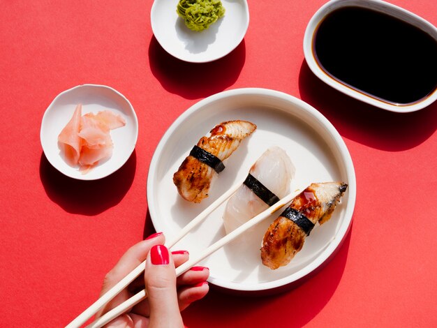 Белые тарелки с суши и васаби на красном фоне