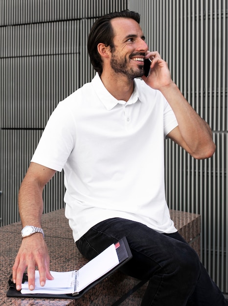 Free photo white polo shirt man talking on the phone menswear apparel fashion