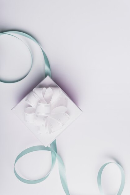 White present box with curled turquoise ribbon isolated on white background