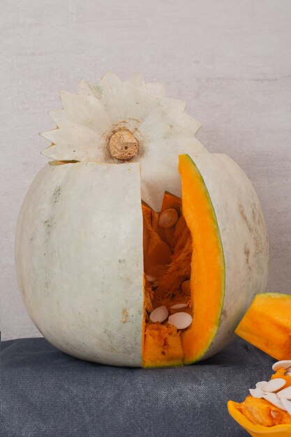 White pumpkin and pumpkin seeds on blue tablecloth.