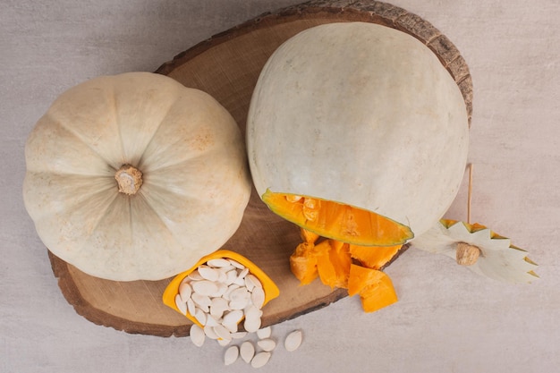 Foto gratuita zucca bianca e semi di zucca sul tavolo bianco.