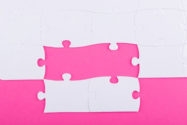 Бесплатное фото Белые кусочки головоломки и розовый фон