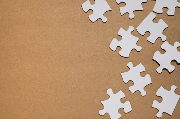 White puzzle pieces on brown paper backdrop