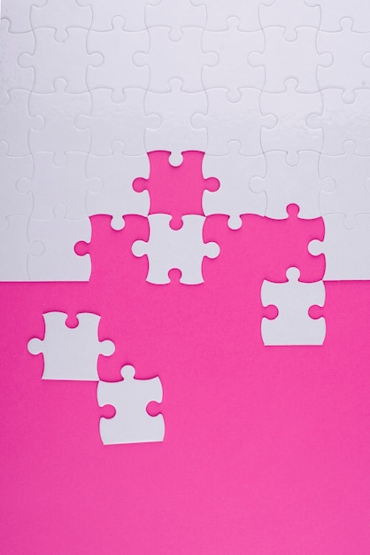 White puzzle pieces and pink background top view