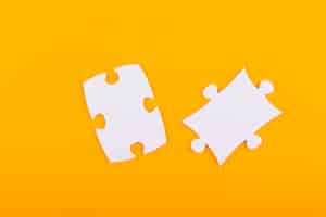 Foto gratuita pezzi di puzzle bianchi con sfondo arancione