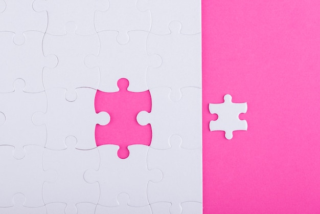 Free photo white puzzle pieces with pink background