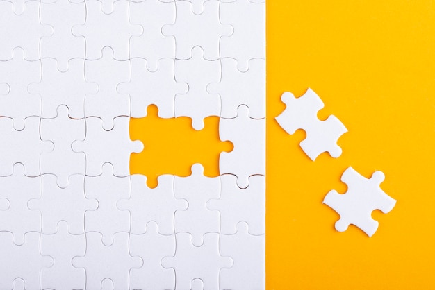 Free photo white puzzle pieces and yellow background above view