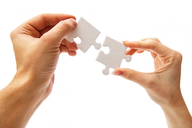 Two hands holding matching pieces of white puzzle
