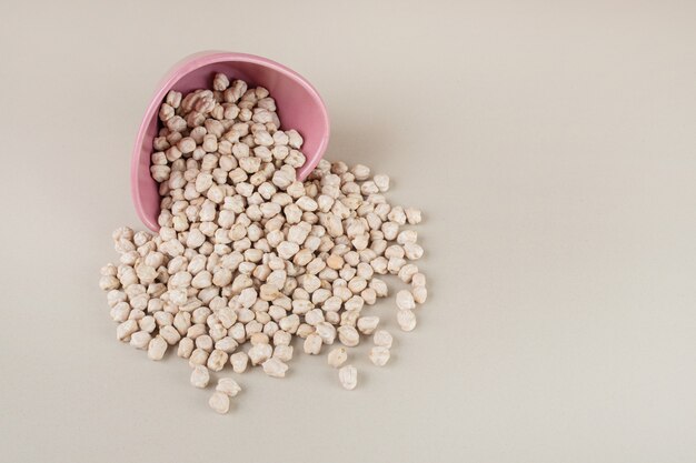 White raw pea beans in a metallic cup on concrete.