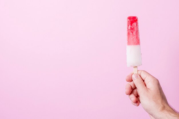 Белое и красное холодное мороженое на палочке с копией пространства