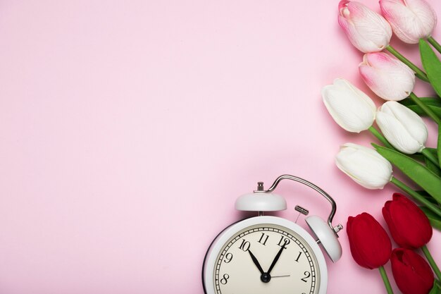 White and red tulips beside clock with copy-space