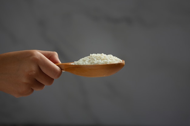 White rice is held in a spoon by the hand holding the spoon.