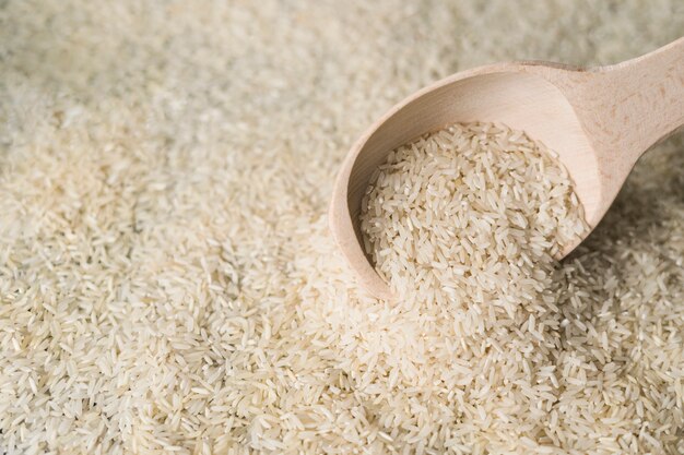 White rice in wooden spoon on backdrop