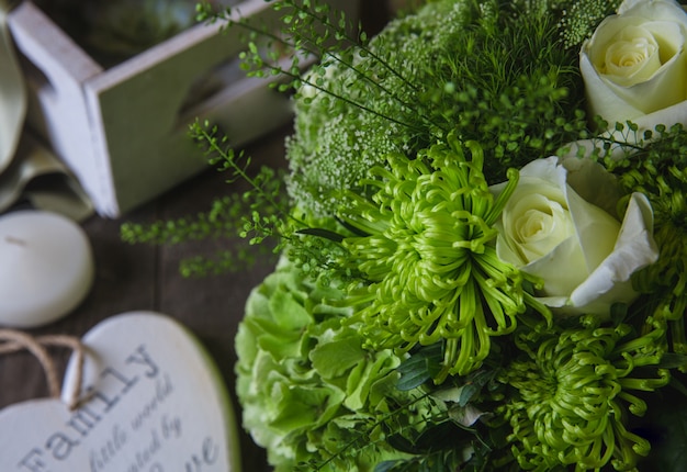 White roses and green chrysanthemums bouquet with wooden symbols around.