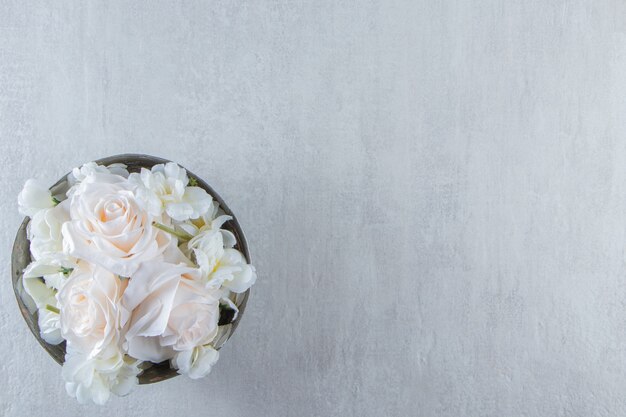 흰색 테이블에 철 그릇에 흰 장미.
