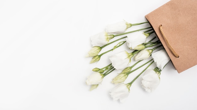 White roses in a paper gift bag top view