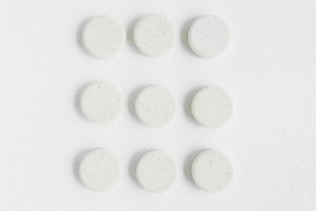 White round pills arranged on isolated backdrop